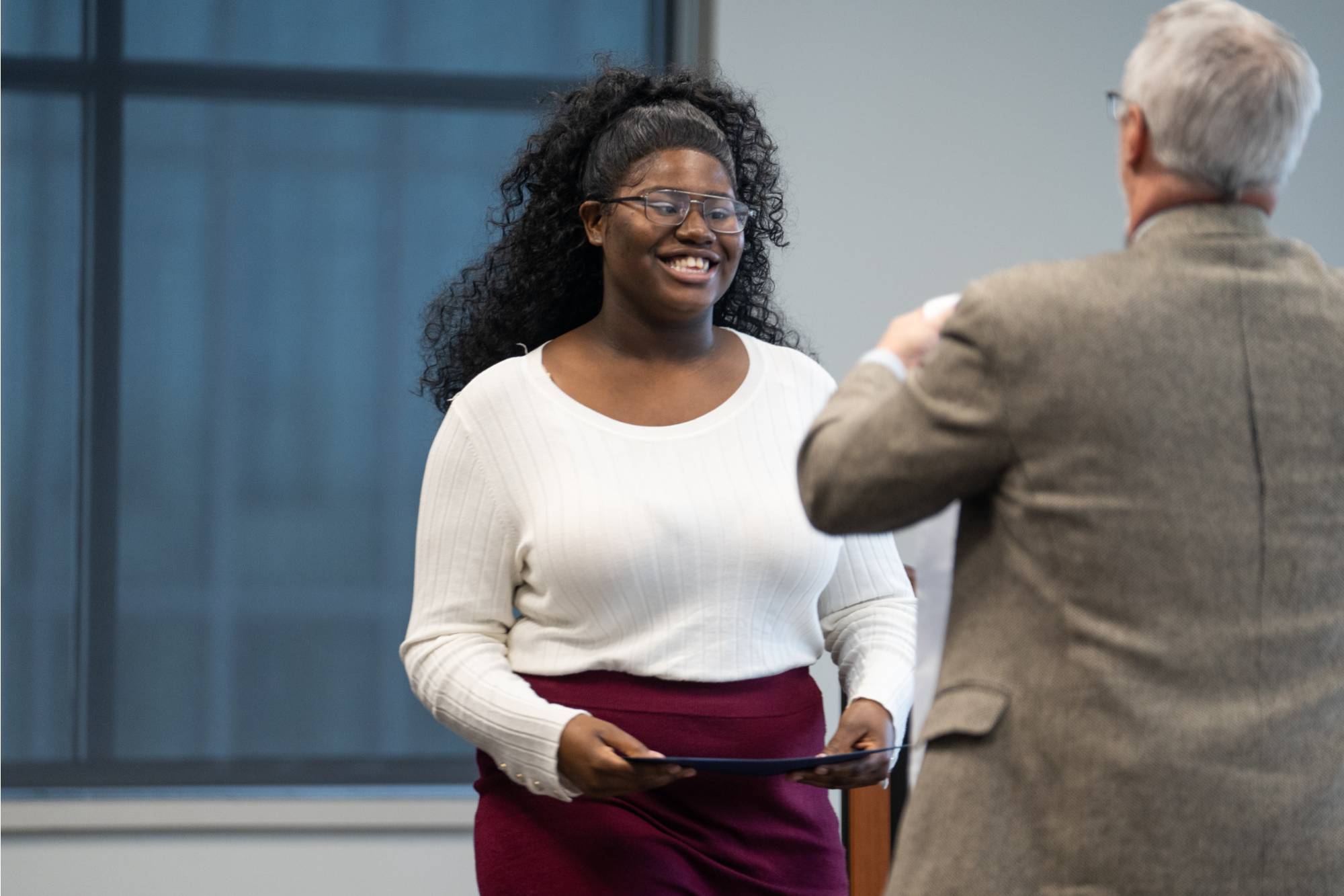 Honors graduate smiling while receiving their stole